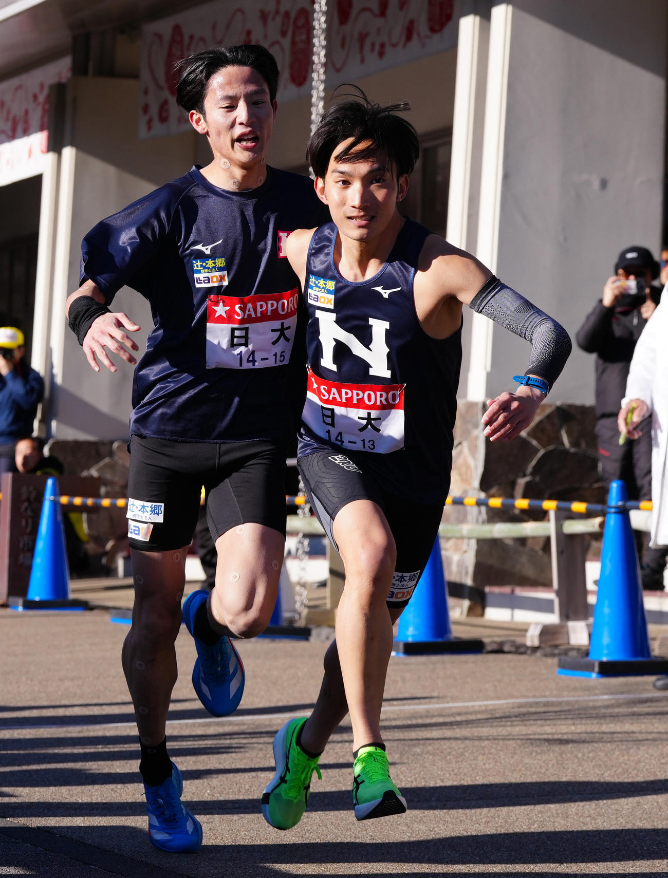小田原中継所で7区天野（右）にたすきを渡す日大6区山口（撮影・鈴木みどり）