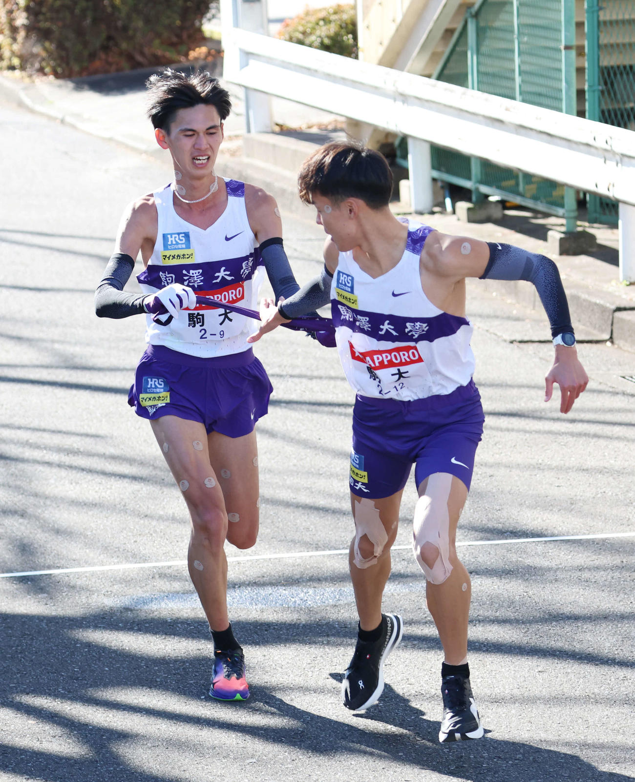 鶴見中継所で10区佐藤（右）にタスキリレーをする駒大9区菅谷（撮影・増田悦実）