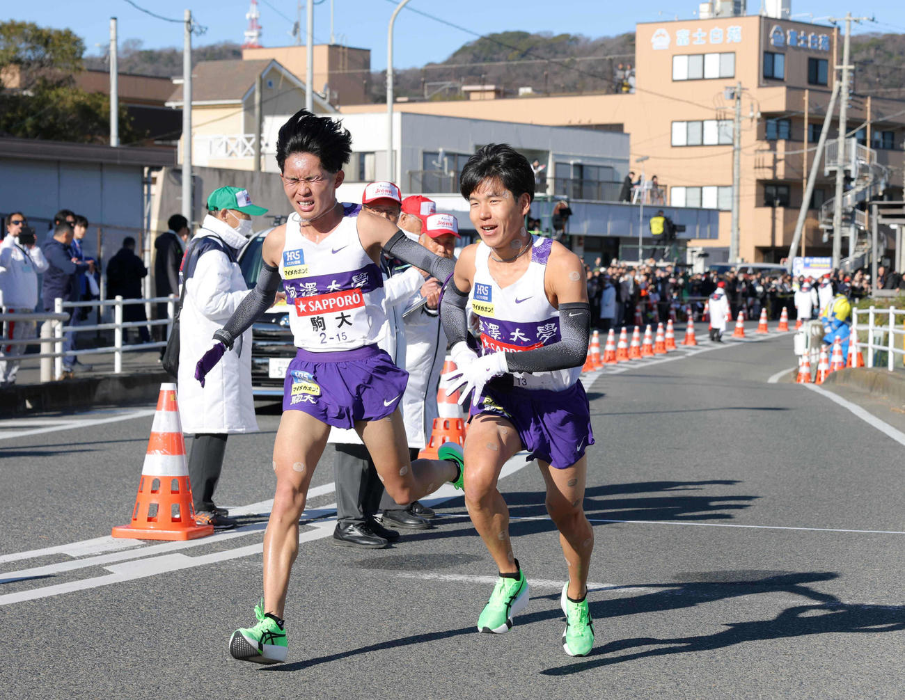 7区谷中（左）からたすきを受け取る駒大8区山川（代表撮影）