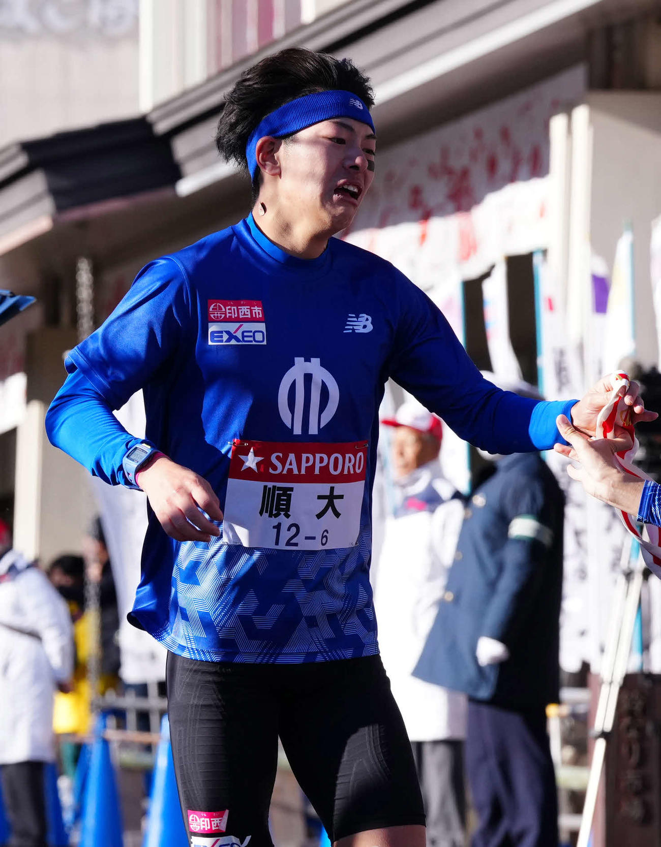 小田原中継所で7区玉目にたすきを渡す順大6区谷本（撮影・鈴木みどり）