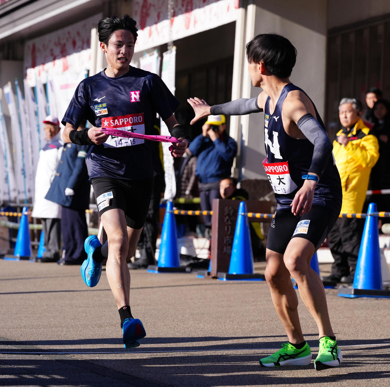 小田原中継所で7区天野（右）にたすきを渡す日大6区山口（撮影・鈴木みどり）