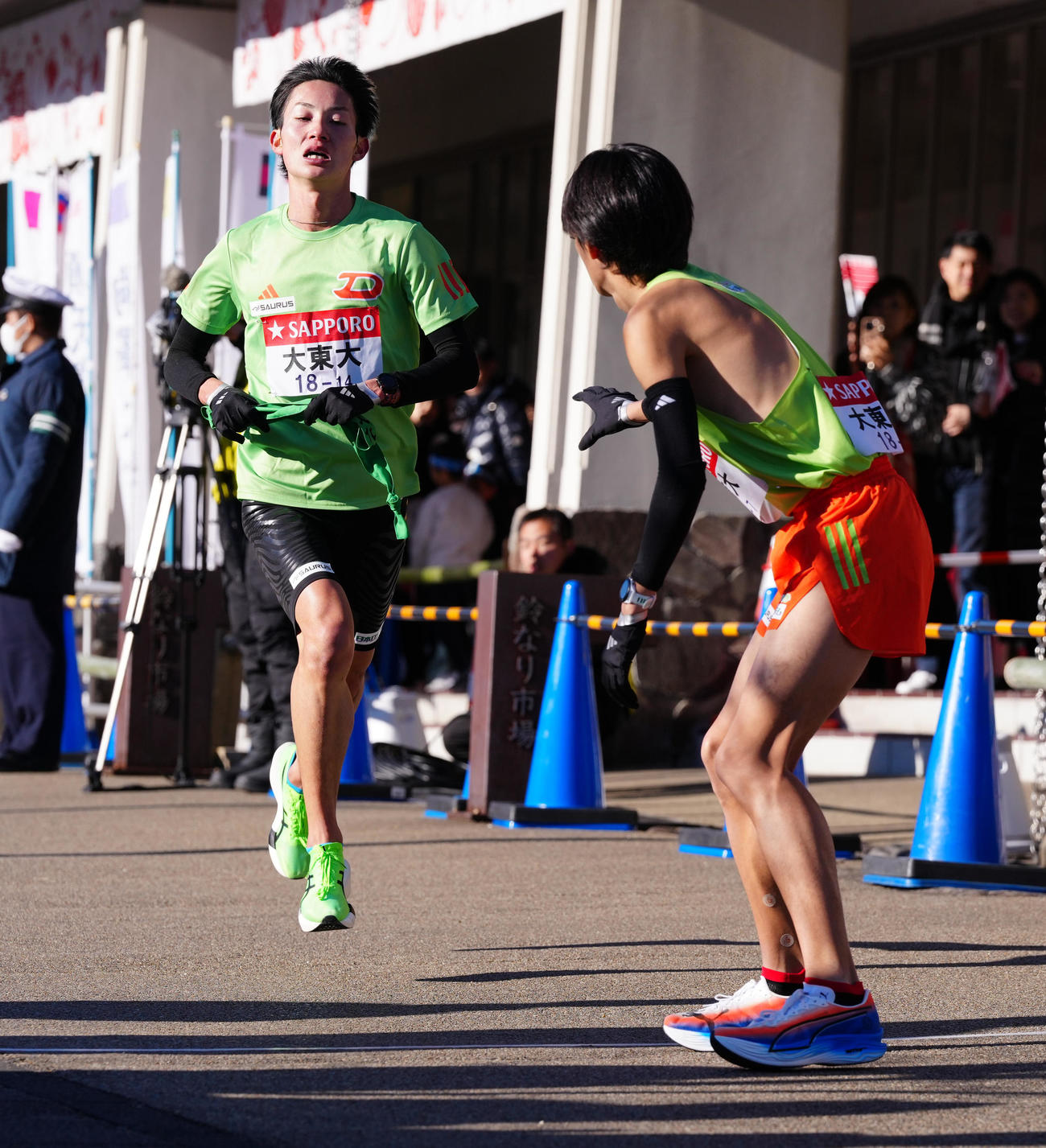 小田原中継所で7区中沢（右）にたすきを渡す大東大6区戸田（撮影・鈴木みどり）