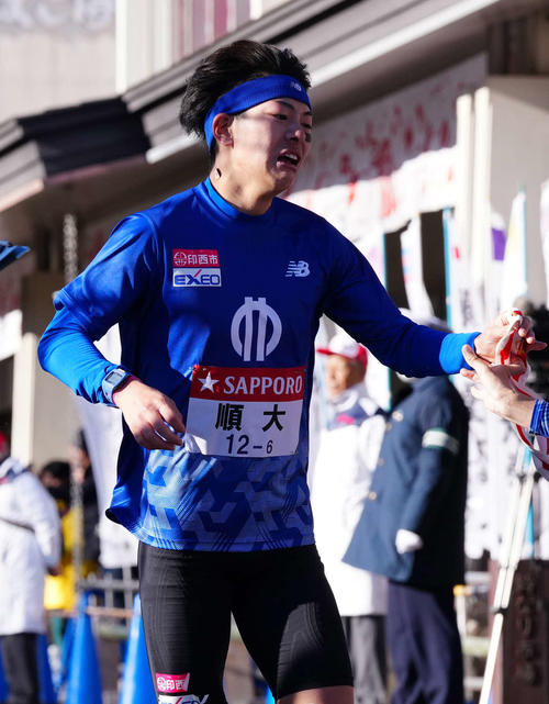 小田原中継所で7区玉目にたすきを渡す順大6区谷本（撮影・鈴木みどり）