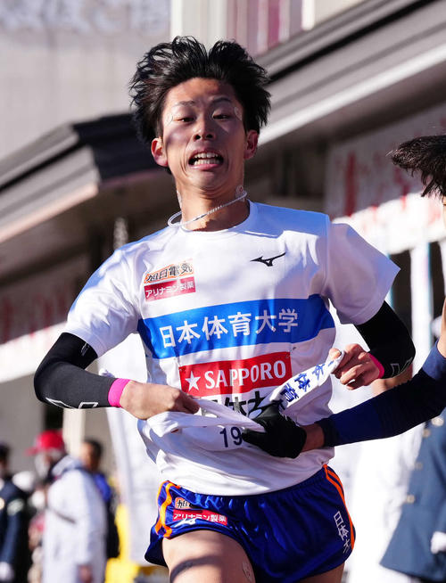 小田原中継所で7区二村にたすきを渡す日体大6区山上（撮影・鈴木みどり）