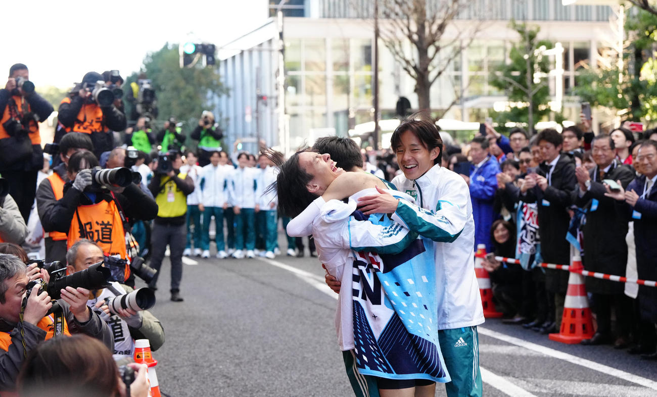 箱根駅伝総合優勝のゴールテープを切った青学大10区折田（中央）と抱き合う黒田。右は塩出（撮影・江口和貴）