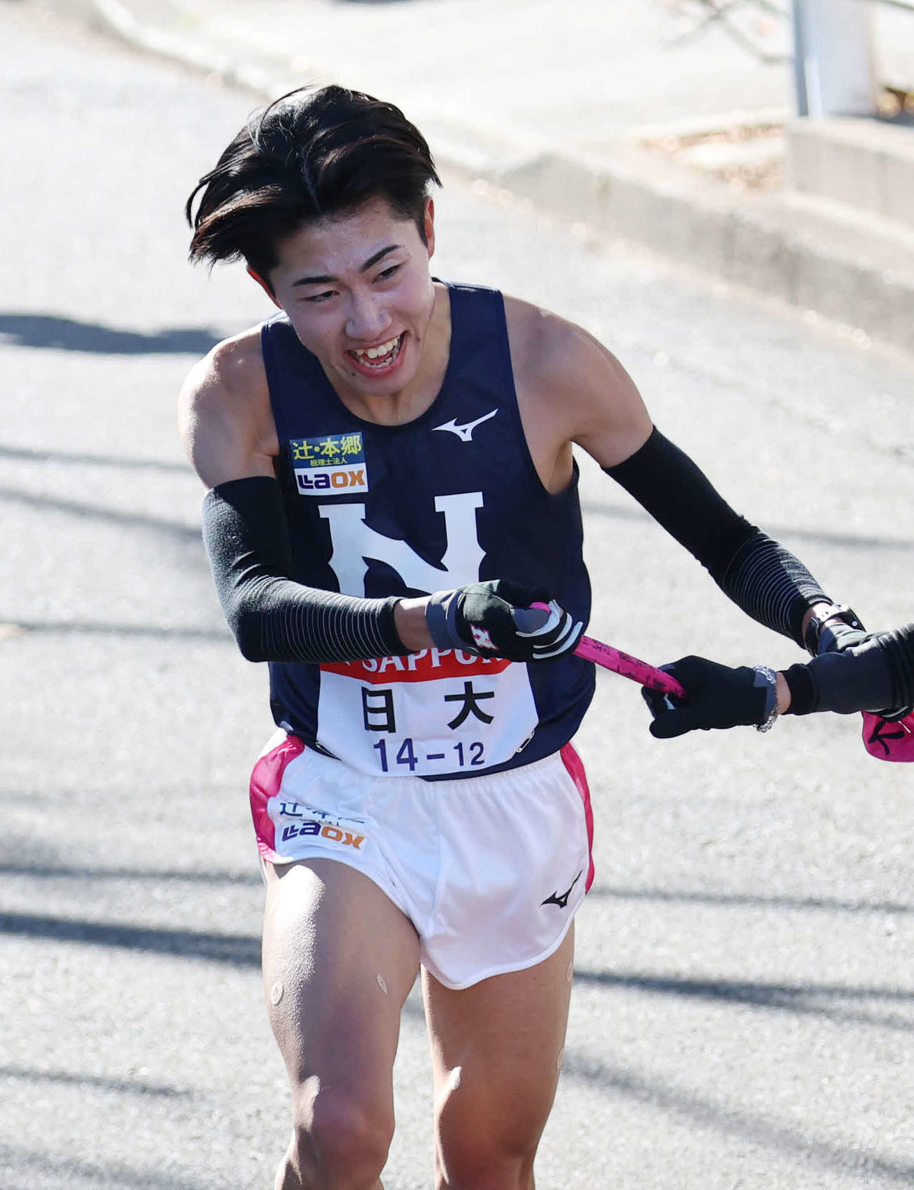 鶴見中継所で10区大仲（右）にタスキリレーをする日大9区中沢（撮影・増田悦実）