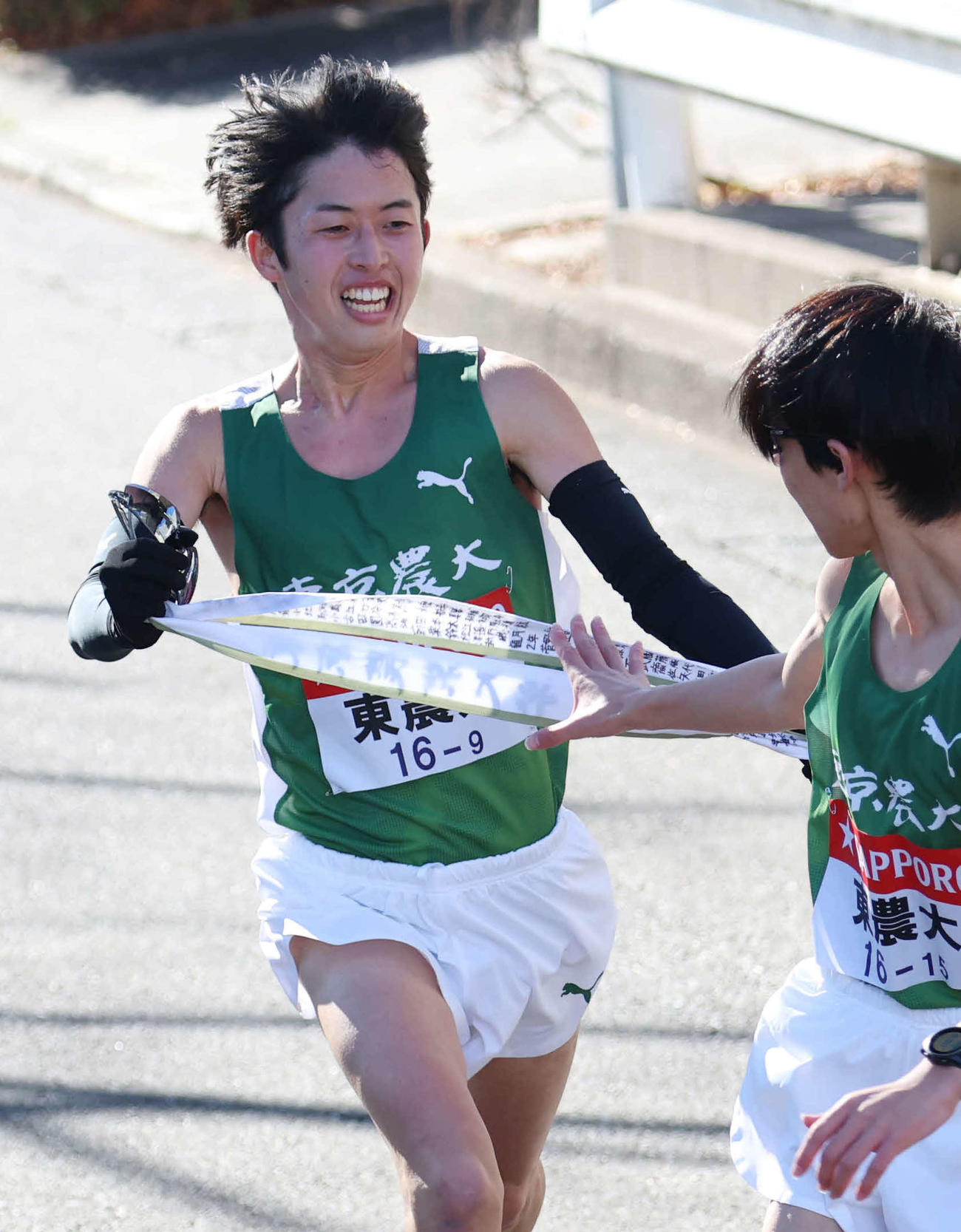 鶴見中継所で10区井坂（右）にタスキリレーをする東農大9区菅野（撮影・増田悦実）