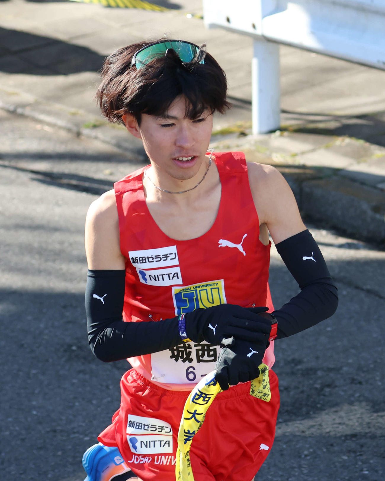 鶴見中継所でタスキを受け取り走り出す城西大10区岩田（撮影・増田悦実）