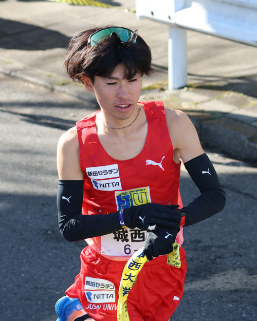 鶴見中継所でタスキを受け取り走り出す城西大10区岩田（撮影・増田悦実）