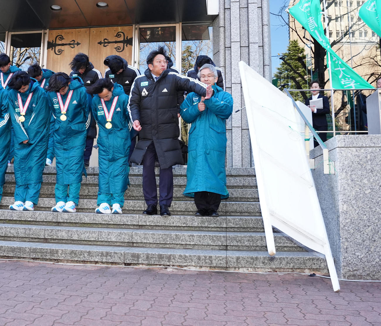 箱根駅伝優勝報告会中、強風で立て看板が動き、手を前に出す青学大・原監督（右から2人目）（撮影・江口和貴）