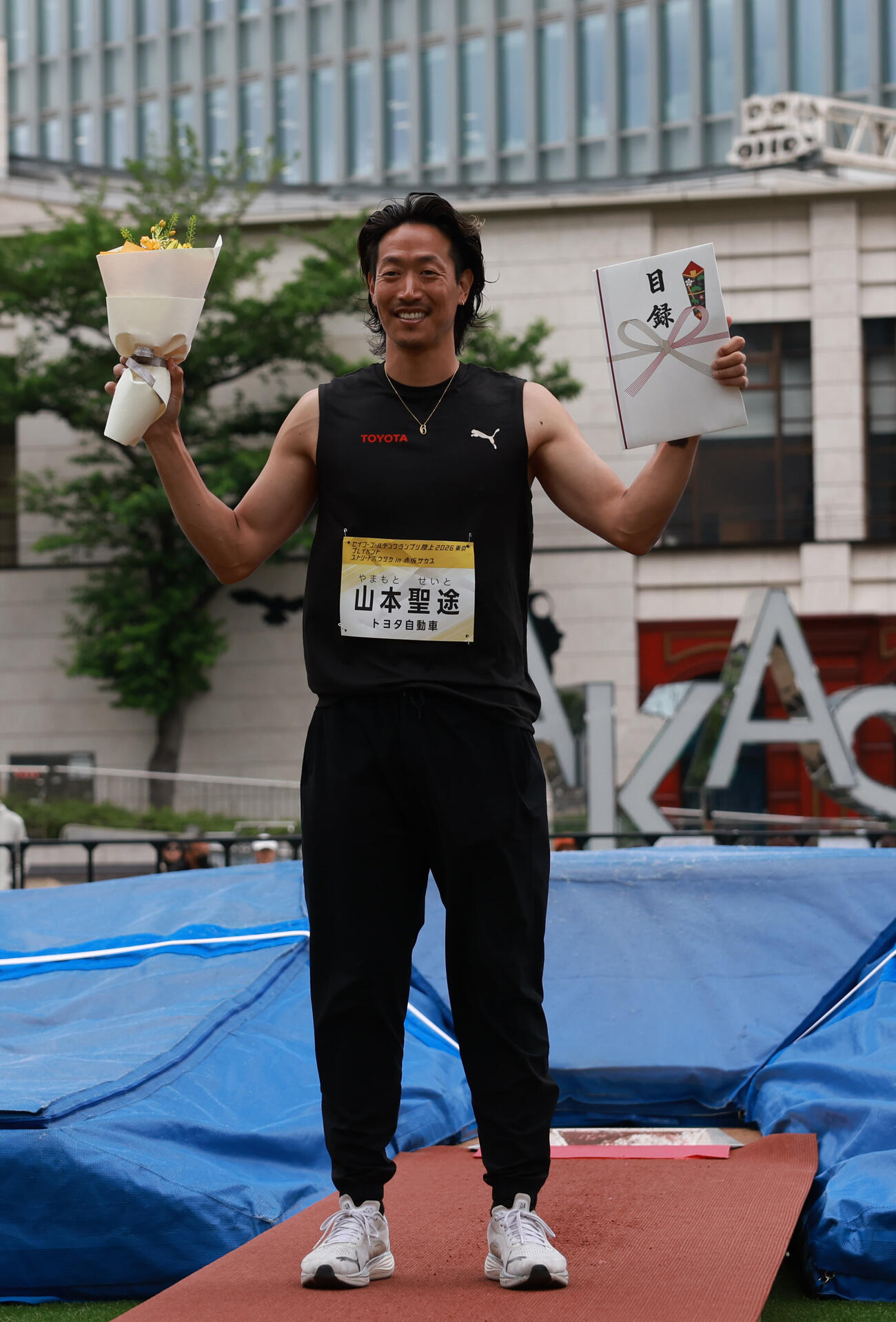 セイコーゴールデングランプリ2026プレイベントで「ストリートボウタカ」を披露する山本聖途。5メートル20を飛び優勝し目録と花束を手に笑顔（撮影・水谷安孝）