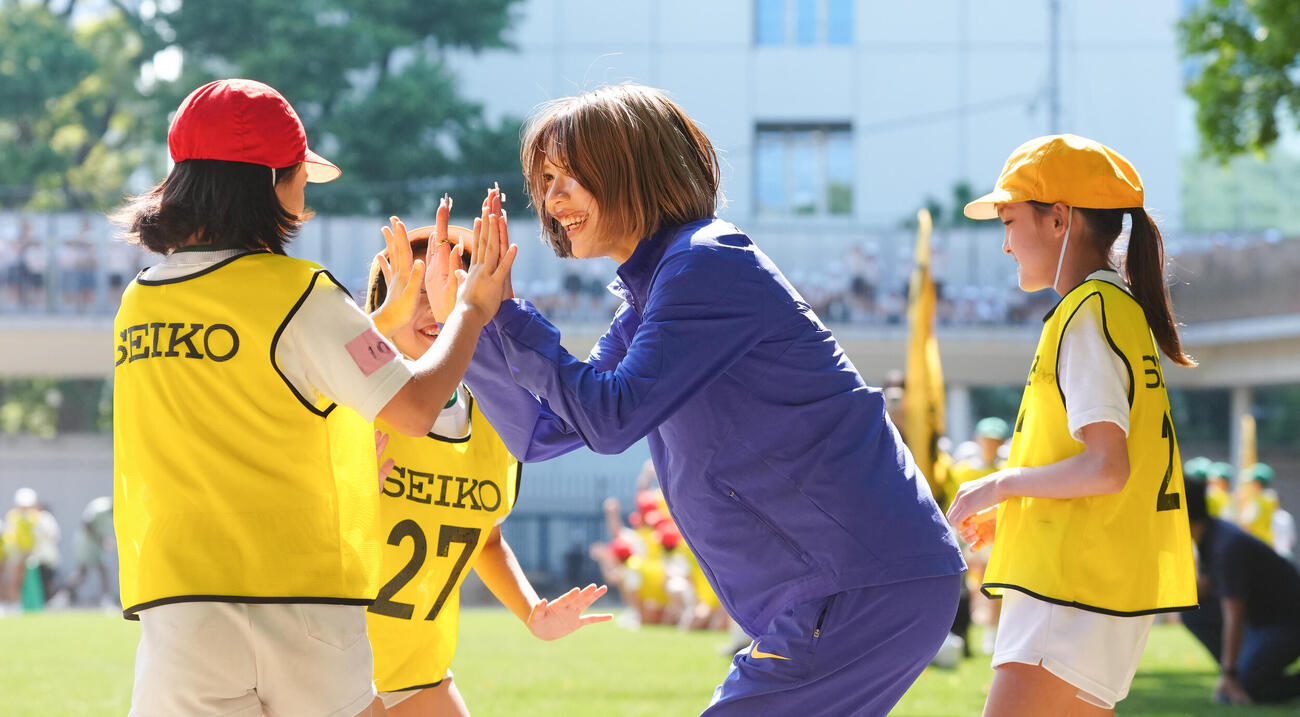 「RIKUJO JAPAN　小学校訪問陸上交流会」で子供たちと競争した後、ハイタッチする中島ひとみ（中央）（撮影・鈴木みどり）