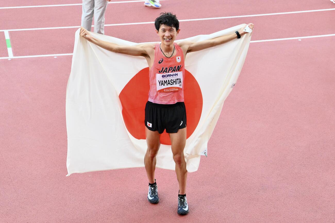 男子マラソンで優勝を決め日の丸を背に記念撮影する山下一貴（撮影・滝沢徹郎）