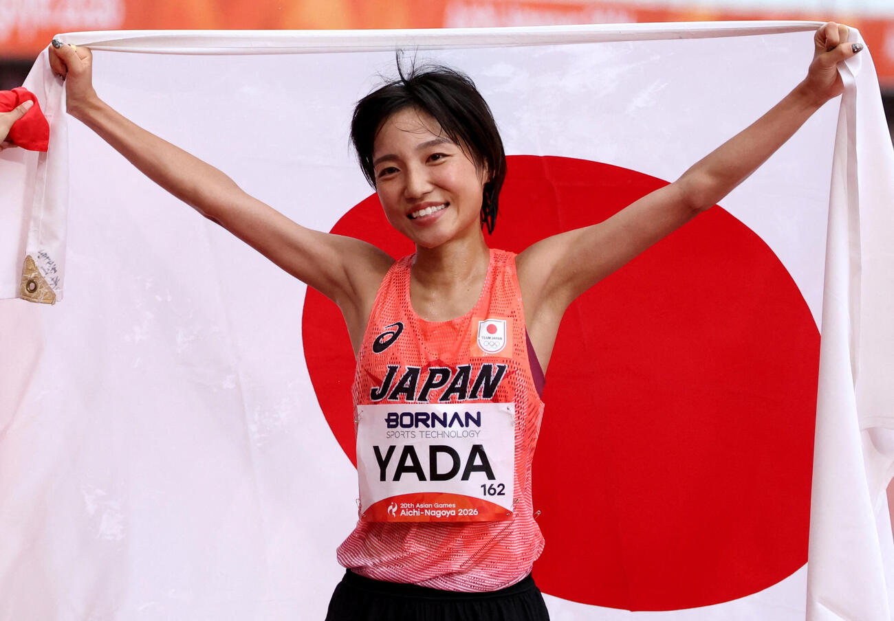 アジア大会女子マラソンで銅メダルを獲得し、日の丸を手に笑顔の矢田みくに（ロイター）