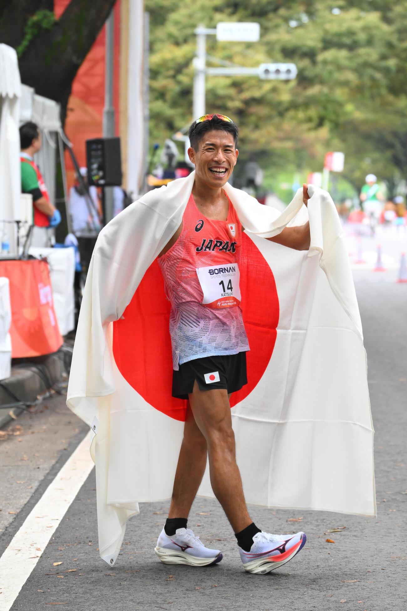 男子マラソン競歩で優勝を決めた勝木隼人は日の丸を背にポーズを決める（撮影・滝沢徹郎）