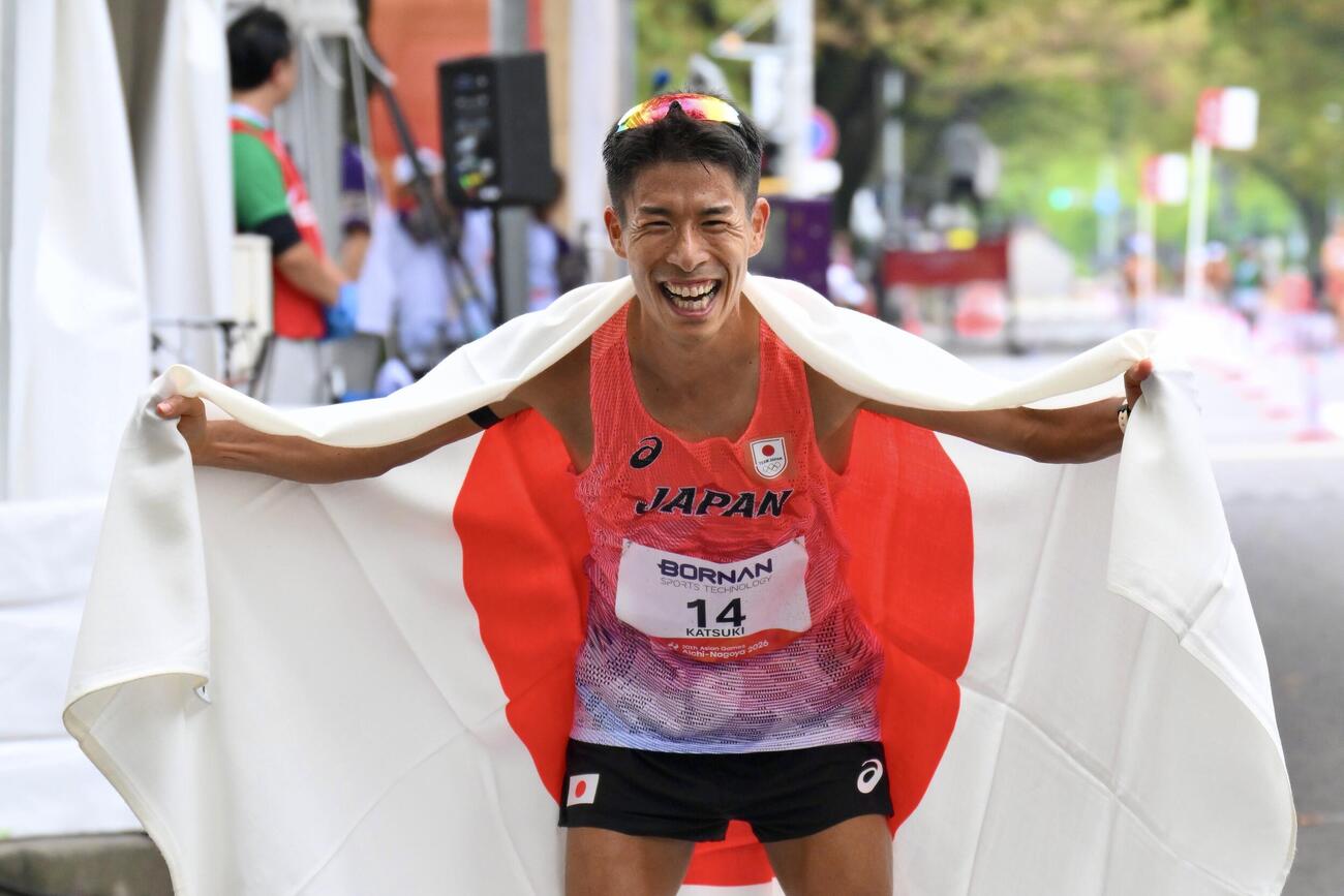 男子マラソン競歩で優勝を決めた勝木隼人は日の丸を背にポーズを決める（撮影・滝沢徹郎）
