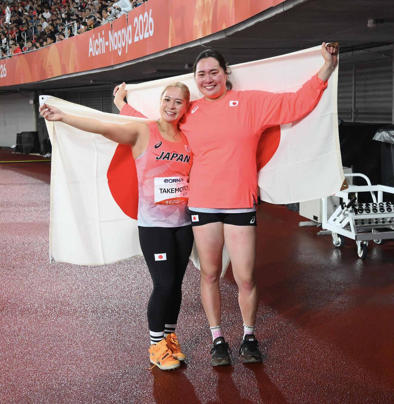 女子やり投げで準優勝の北口榛花（右）と銅メダルの武本紗栄は日の丸を背に記念撮影する（撮影・滝沢徹郎）
