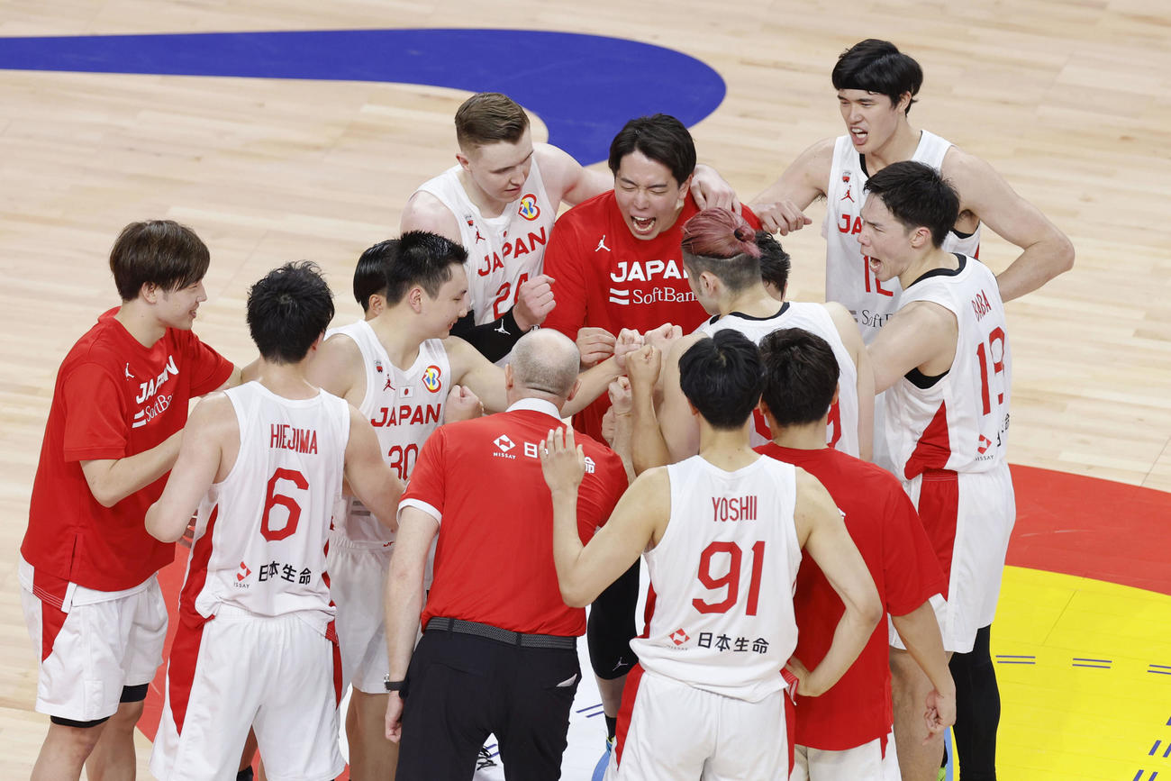 ベネズエラに競り勝ち、コート上に集まり拳を合わせて喜ぶ日本の選手たち（共同）