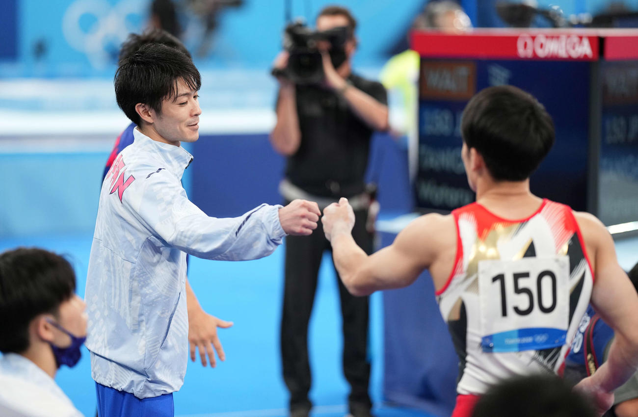 東京五輪、団体予選で平行棒の演技を終えた谷川航（右）を迎える内村
