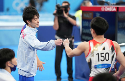 東京五輪、団体予選で平行棒の演技を終えた谷川航(右)を迎える内村