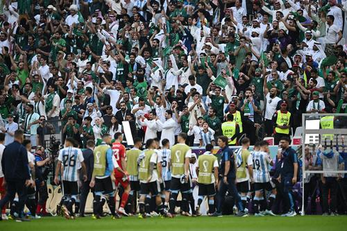 試合に敗れ、引き揚げるアルゼンチンの選手と、勝利を喜ぶサウジアラビアのサポーター（ロイター）