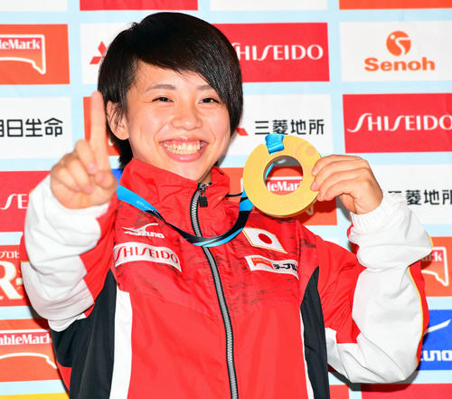 帰国し金メダルを持ちNO・1と指を立てる村上