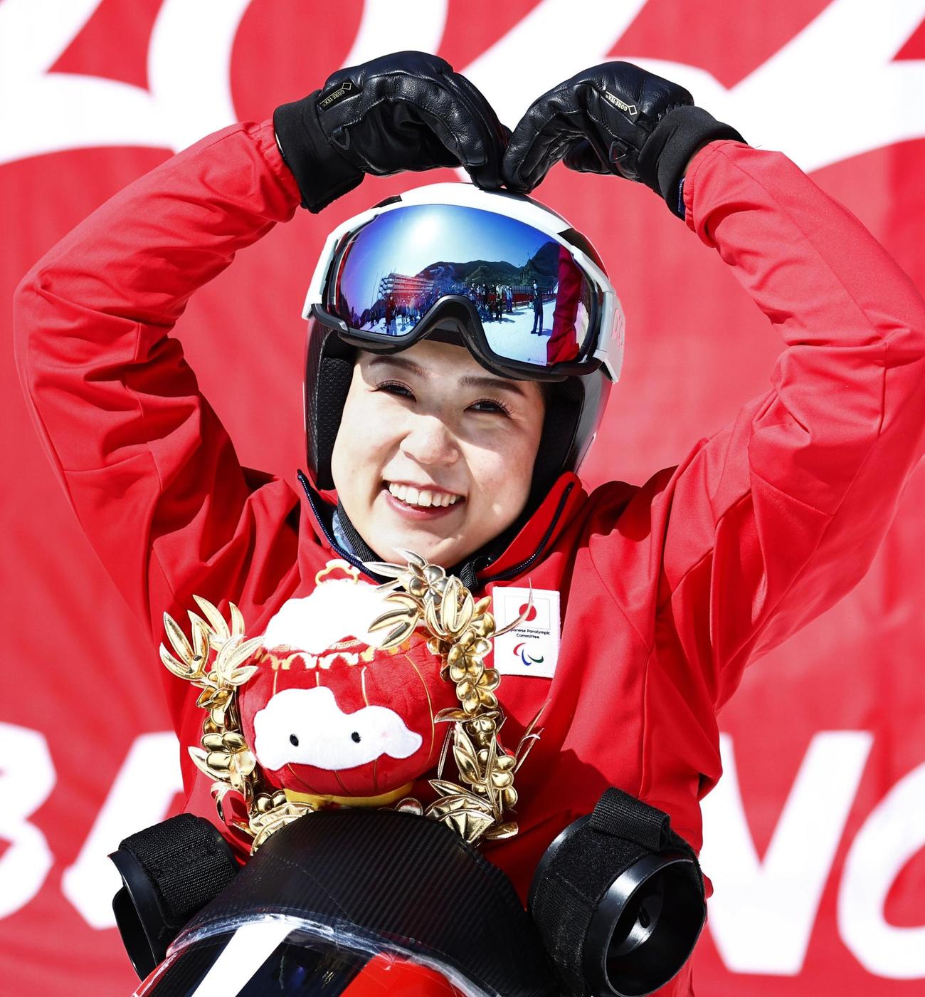 女子スーパー大回転座位で金メダルを獲得し、今大会2冠となった村岡桃佳。大会マスコットを胸に笑顔でポーズをとった＝延慶（共同）