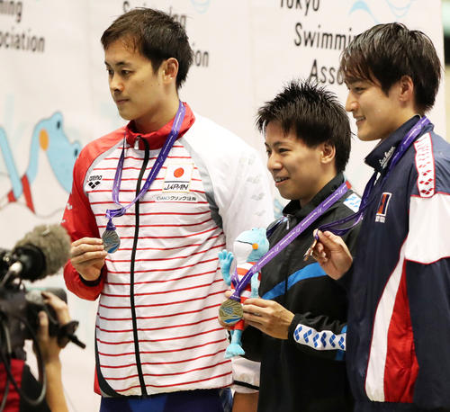 男子１００メートル背泳ぎで２位に終わり、表彰台で銀メダルを掲げる金子（左）。中央は優勝した松原（撮影・林敏行）