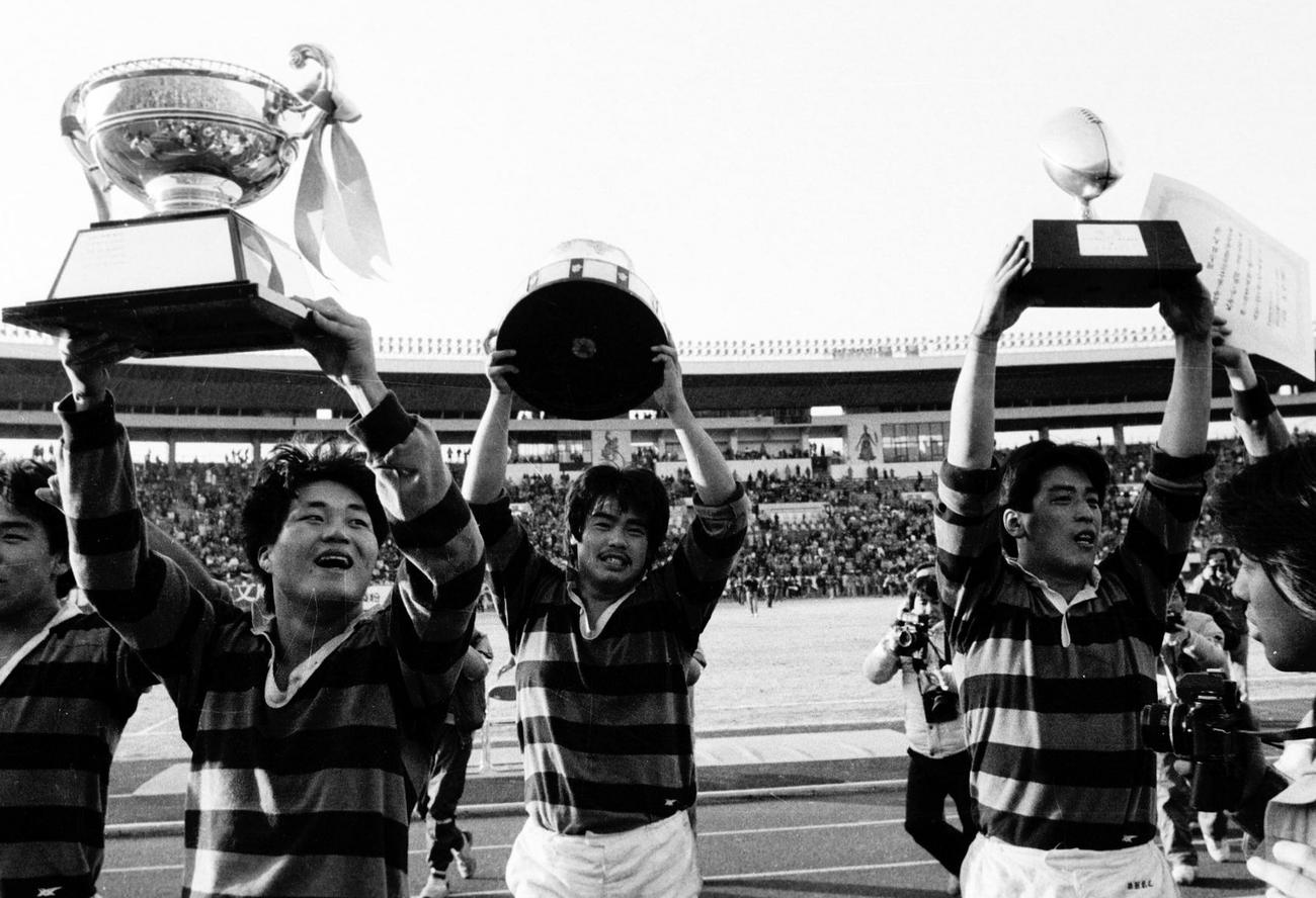 85年1月、大学選手権で優勝しカップを掲げる（左2人目から）同大・円井良、武藤規夫、土田雅人