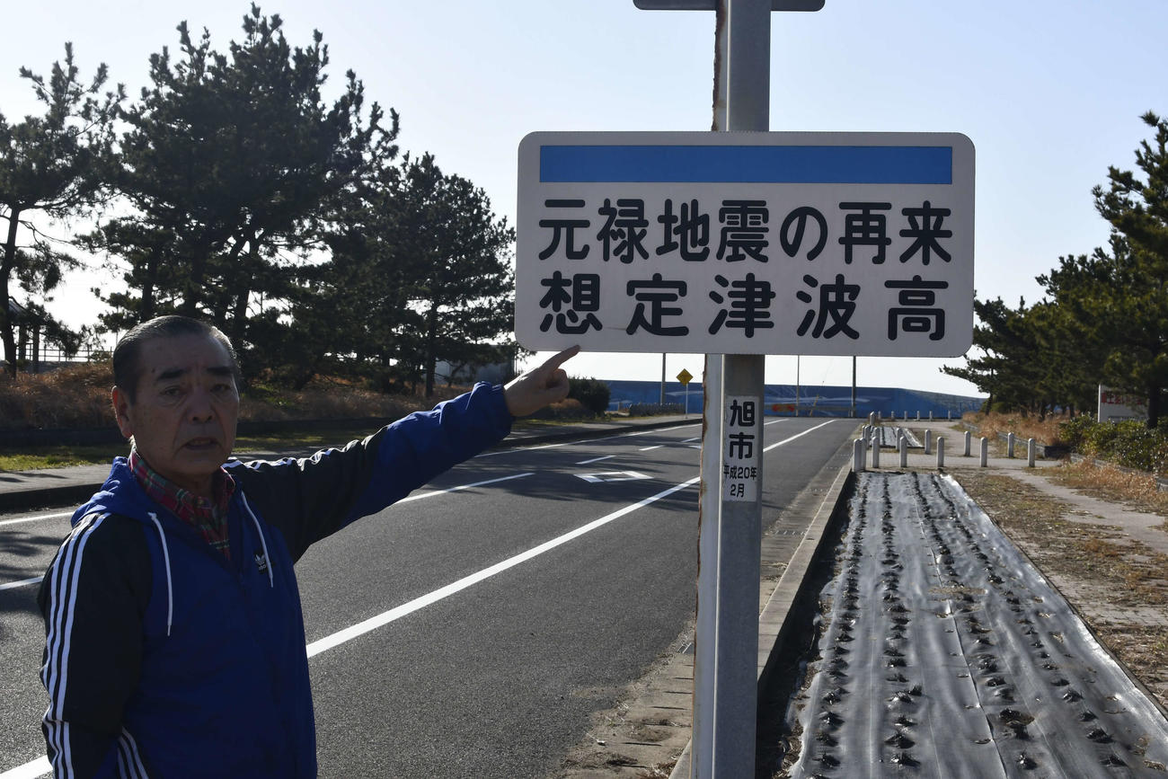 「元禄地震の再来想定津波高」と書かれた看板示す戸井さん（撮影・平山連）
