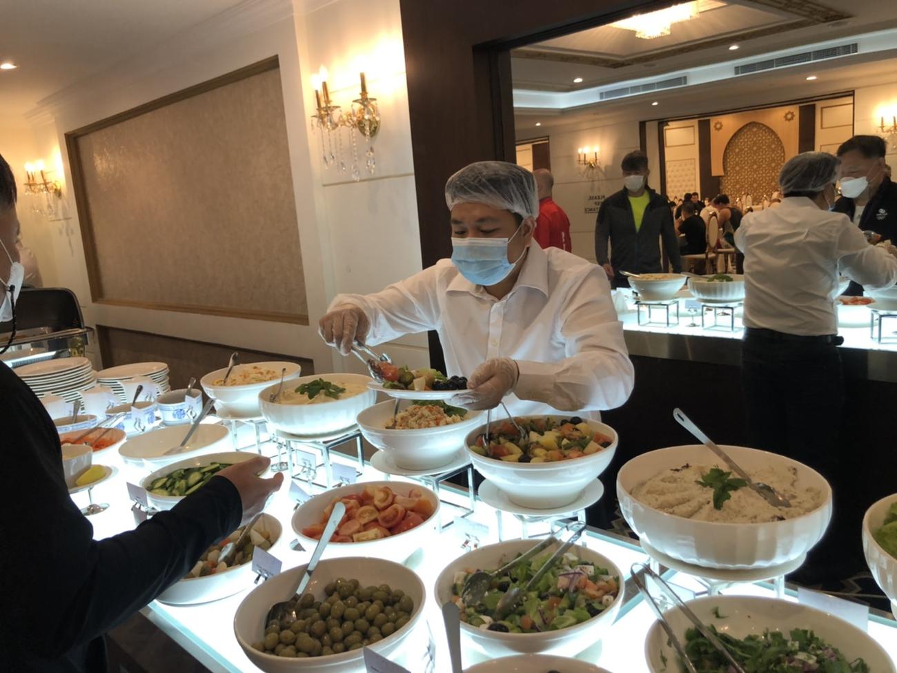 ホテルの食堂で選手らの食事を取り分けるホテル従業員