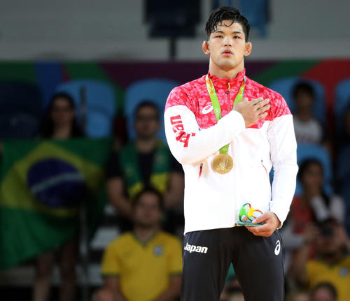 リオデジャネイロ五輪で金メダルの大野将平は日の丸に手を当てて君が代を聞く＝16年8月8日