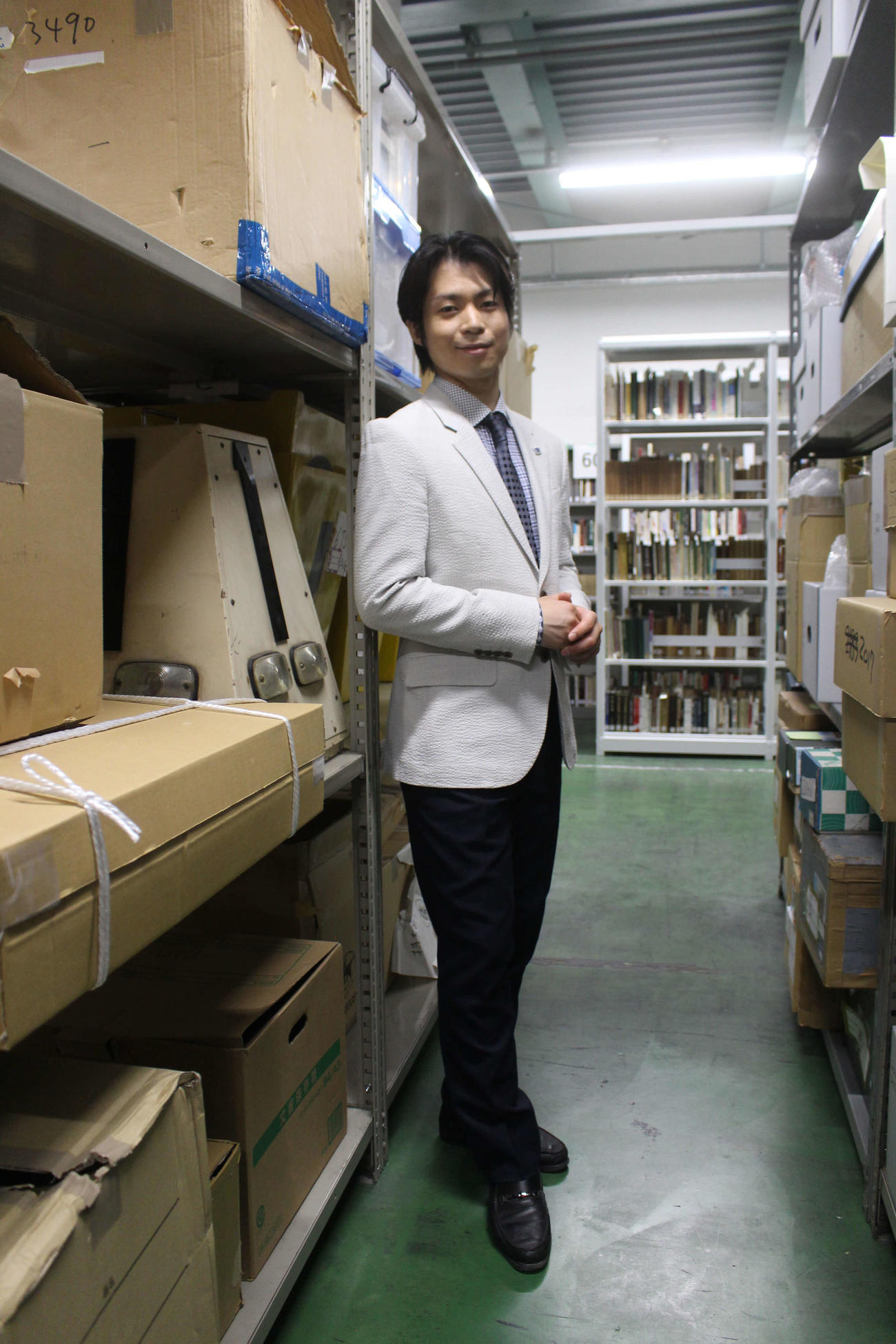 倉庫に収められた収蔵品に囲まれ、その価値を訴える町田さん