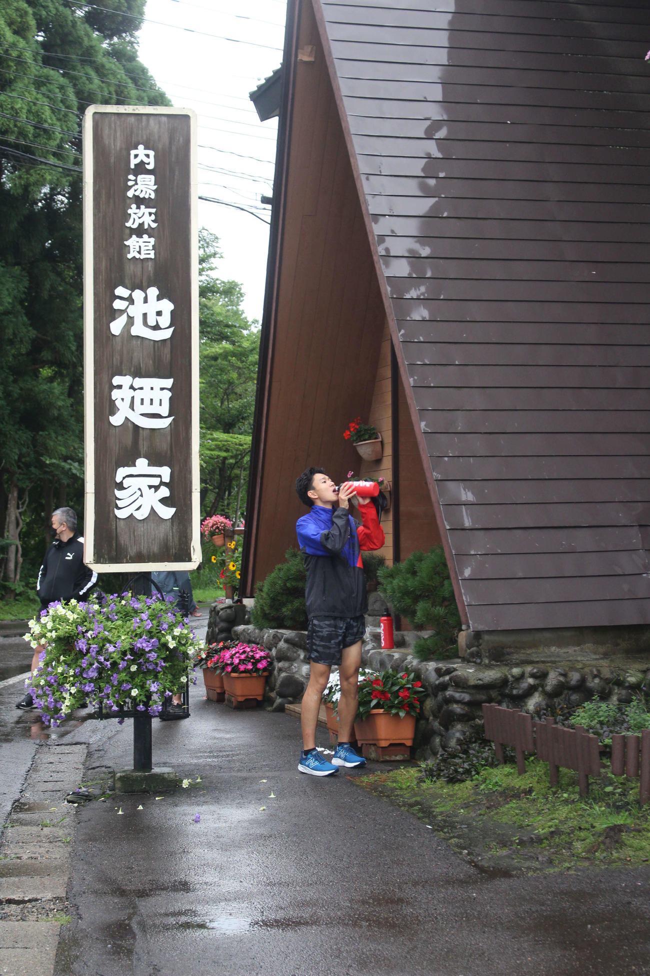 「池廼家」の看板の横で給水するランナー