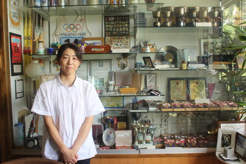 現役時代の記念品の前でほほ笑む横山さん