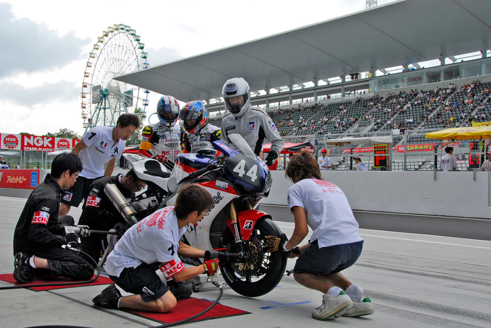 09年の鈴鹿8耐で、タイヤ交換を行う「DDBOYS」のピットクルーたち。新しいタイヤが装着され、アクスルシャフトの締め付けが行われる（撮影・大津賢一）