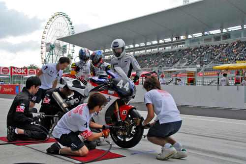 09年の鈴鹿8耐で、タイヤ交換を行う「DDBOYS」のピットクルーたち。新しいタイヤが装着され、アクスルシャフトの締め付けが行われる（撮影・大津賢一）