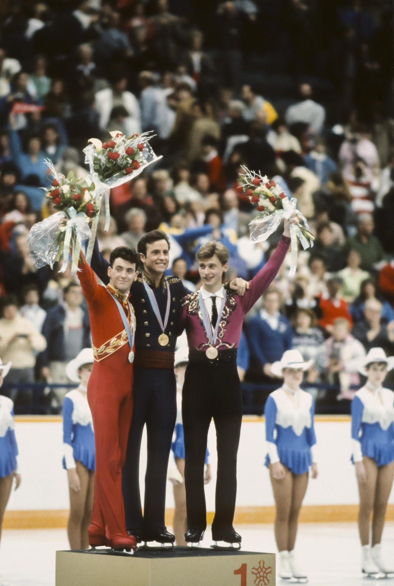 88年2月、「ブライアン対決」となったカルガリー五輪フィギュアスケート男子シングルで優勝したブライアン・ボイタノ（中央）と銀メダルのブライアン・オーサー（左）は表彰台で声援に応える。右は銅メダルのヴィクトール・ペトレンコ（ゲッティ＝共同）
