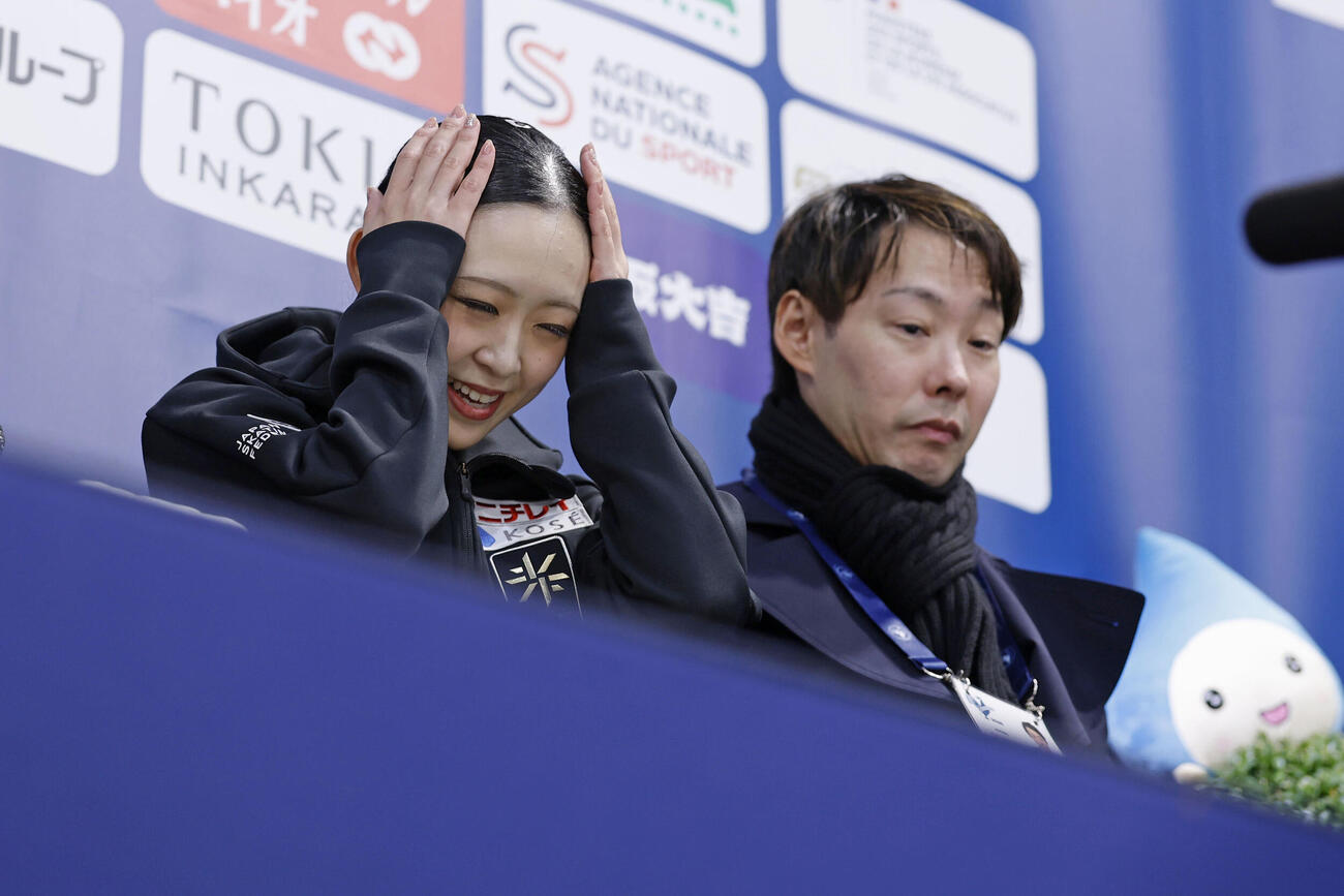 女子フリーの得点を確認した青木祐奈。右は中庭健介コーチ（共同）