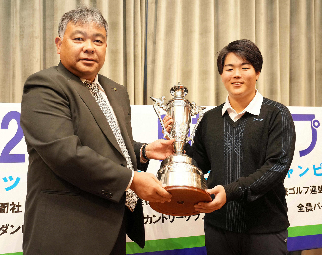 日神グループホールディングス神山隆志代表取締役社長（左）からトロフィーを受け取る23年男子高校の部優勝の志村由羅