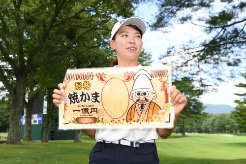 報道陣から1億円のお札状のお菓子を受け取り、笑顔を見せる渋野（撮影・加藤諒）