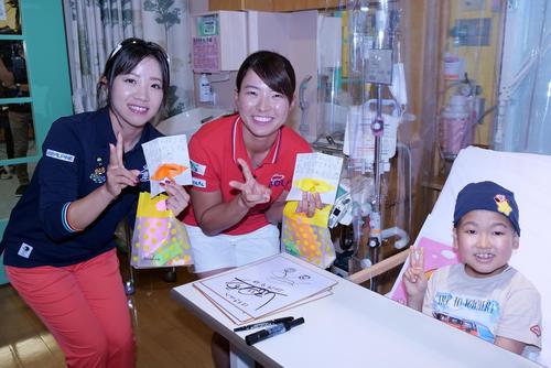 宮城・こども病院を慰問に訪れ、小学生の子どもと笑顔を見せる大江（左）と渋野（大会事務局提供）