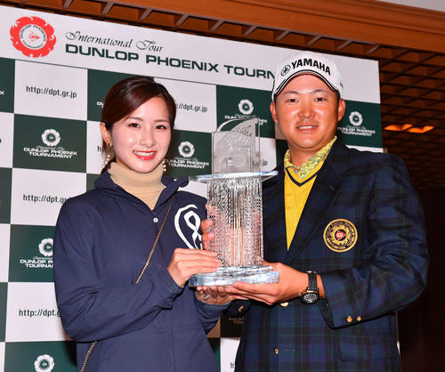 優勝トロフィーを手に笑顔を見せる今平周吾（右）と婚約者の若松奈々恵さん（撮影・上田博志）