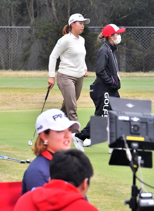 インタビューを受ける鈴木愛の後方でパッティング練習をする渋野日向子（撮影・上田博志）