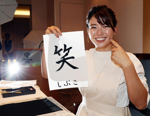 「笑」と毛筆で書いた書を手に笑顔を見せる渋野（撮影・浅見桂子）