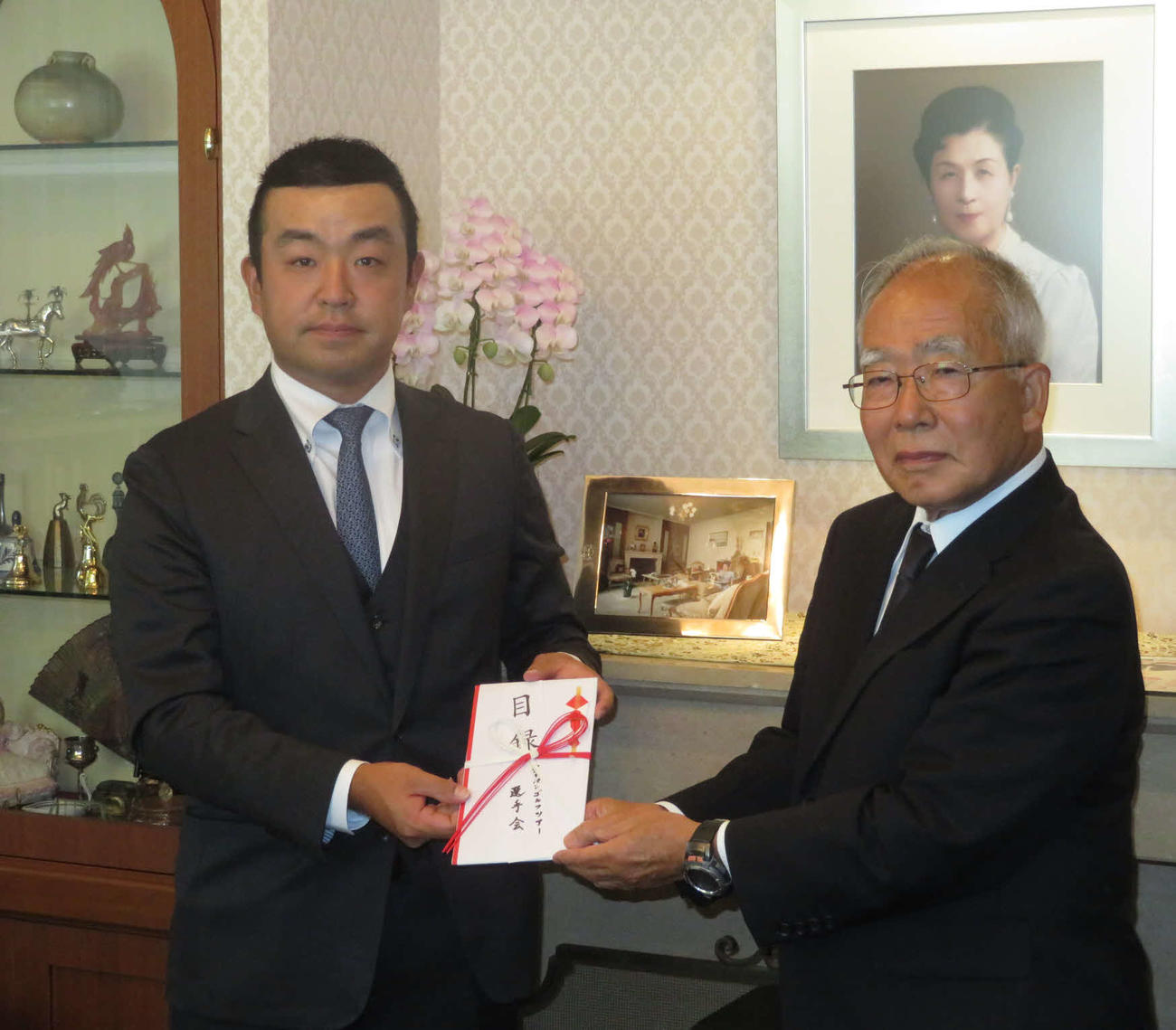 選手会の時松隆光会長（左）は、高松宮妃癌研究基金の関谷剛男理事長に目録を手渡した