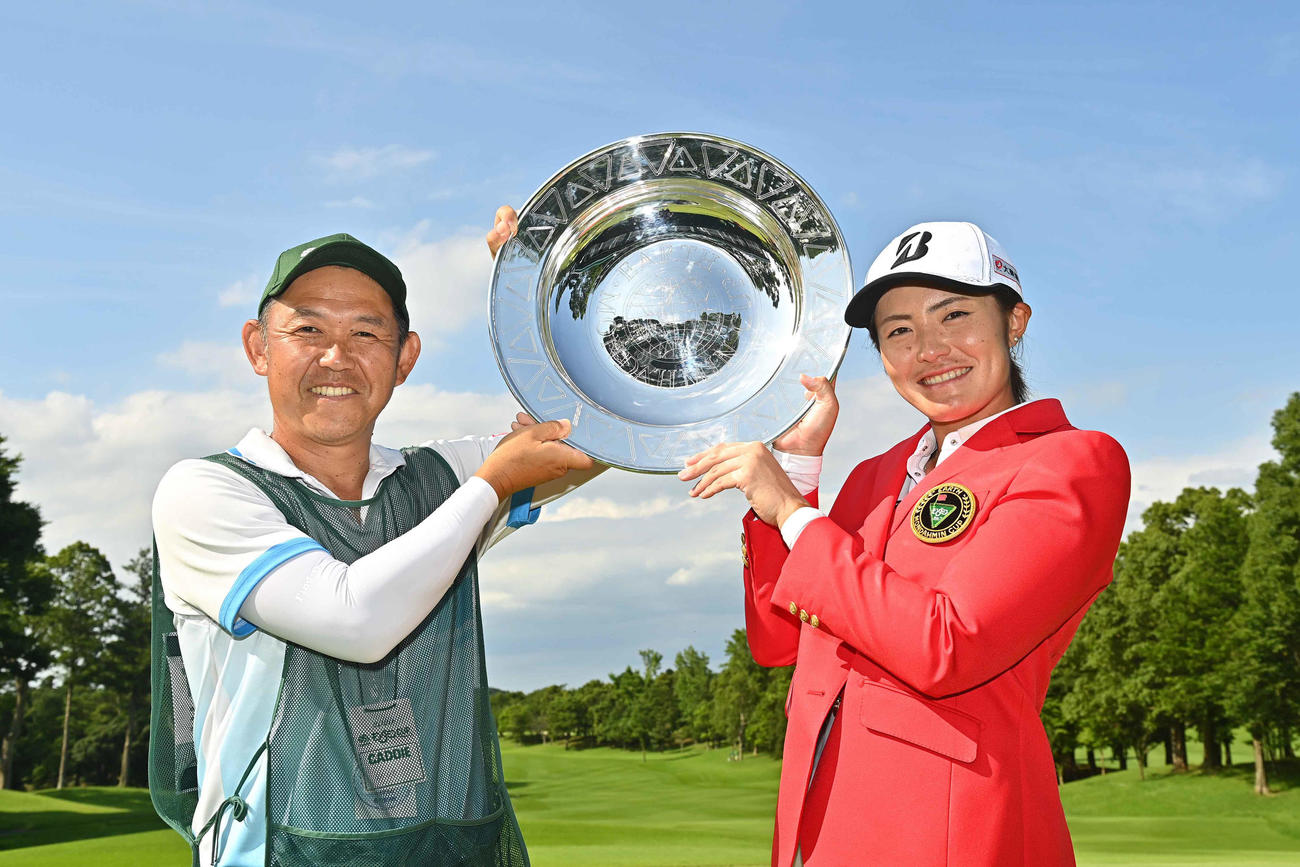 プレーオフを制し5年ぶりのツアー優勝を飾った渡辺は川口キャディーとトロフィーを手に記念撮影する（Getty　Images／JLPGA提供）