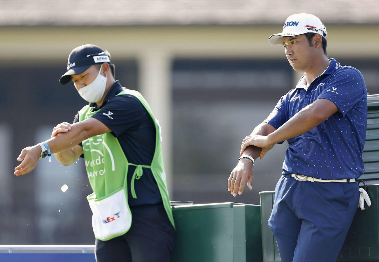 第1ラウンド中に体を冷やす松山英樹（右）と早藤キャディー（共同）