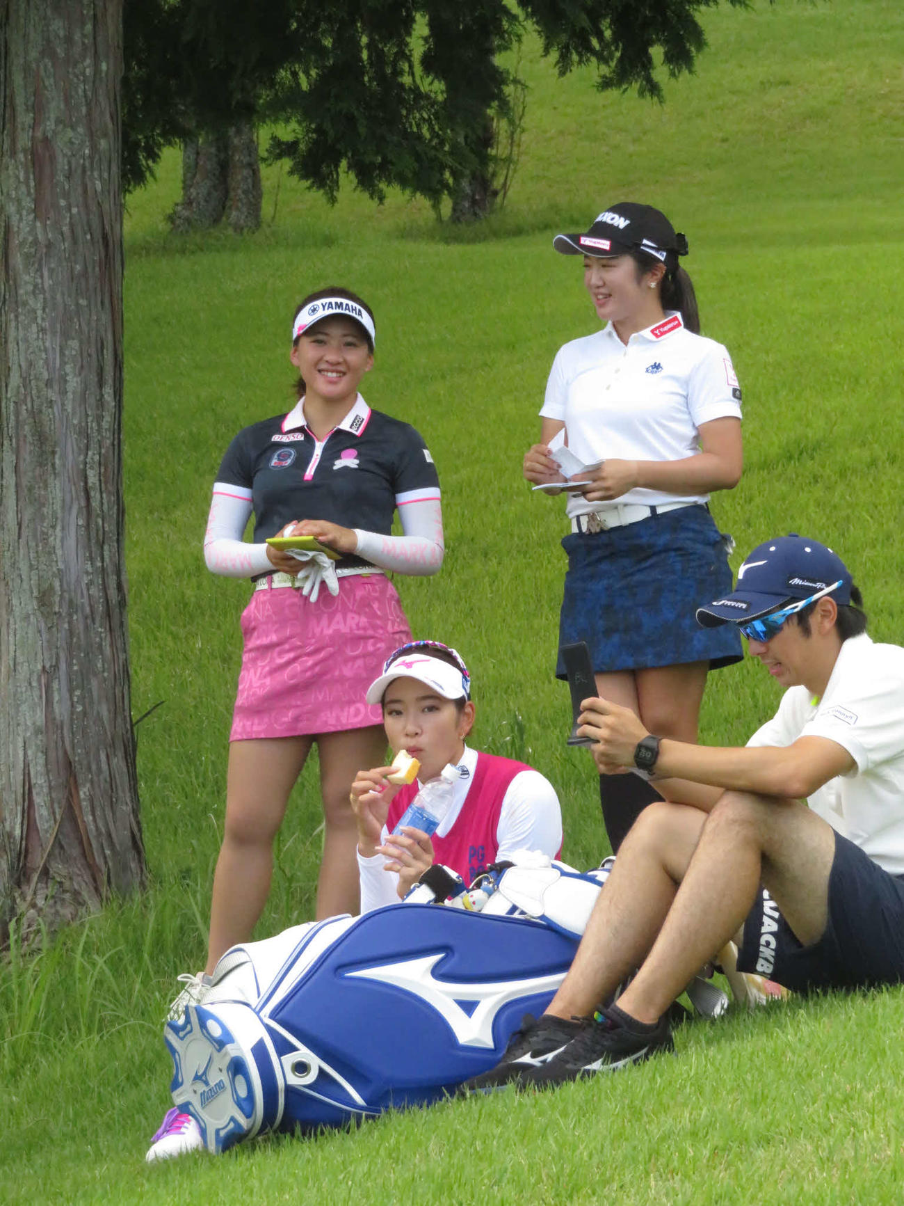 4番、直前にラウンドする組が終わるまで小休憩で栄養補給する原英莉花（手前左）。永井花奈（後方左）と林菜乃子（同右）は談笑