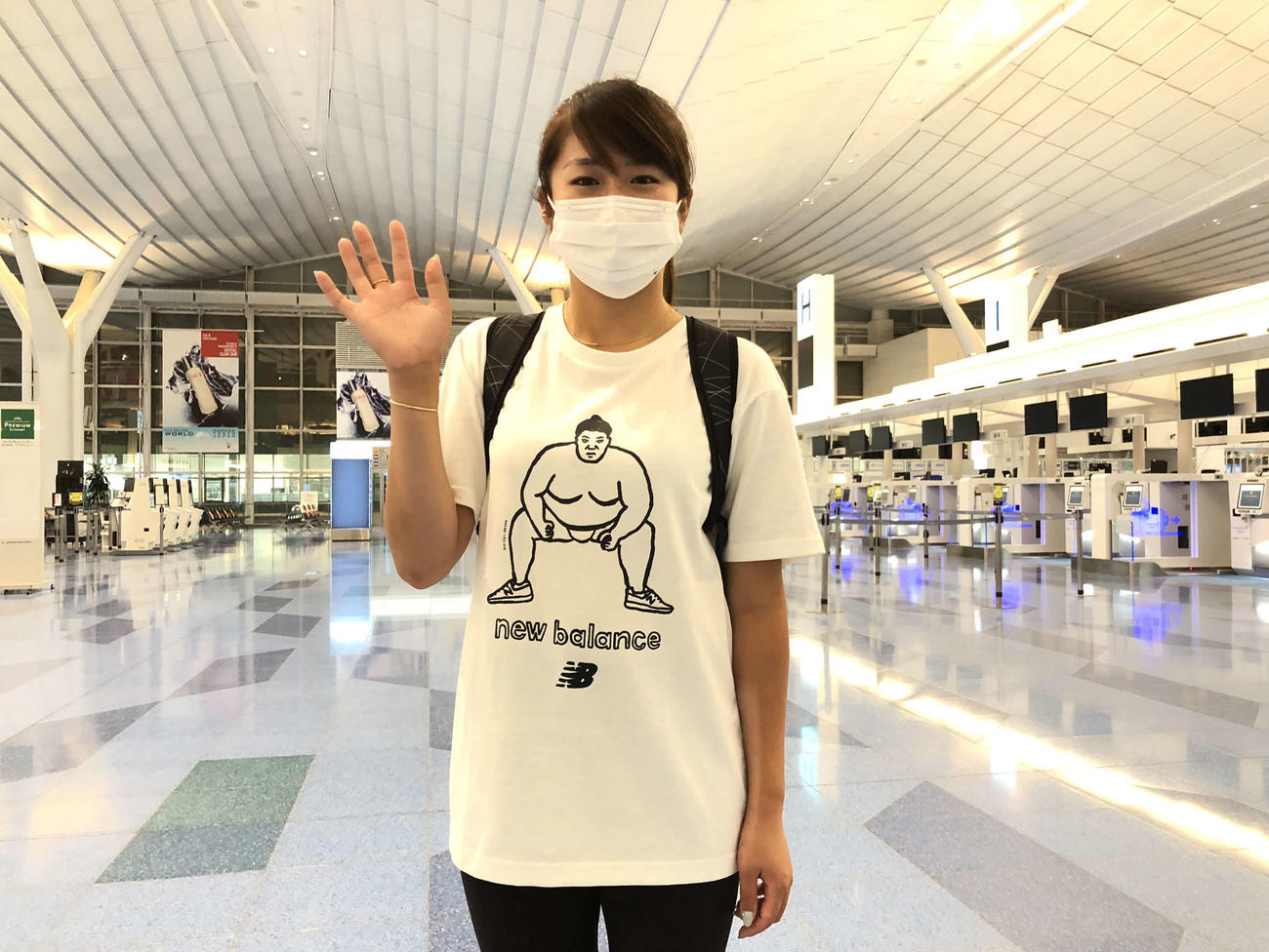 力士がプリントされたTシャツを着て、深夜便で羽田空港から出発する稲見（本人提供）